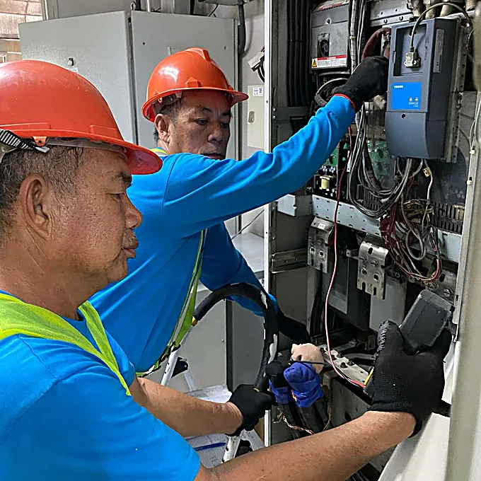 Bestcor technicians servicing a motor-control / VFD cabinet.